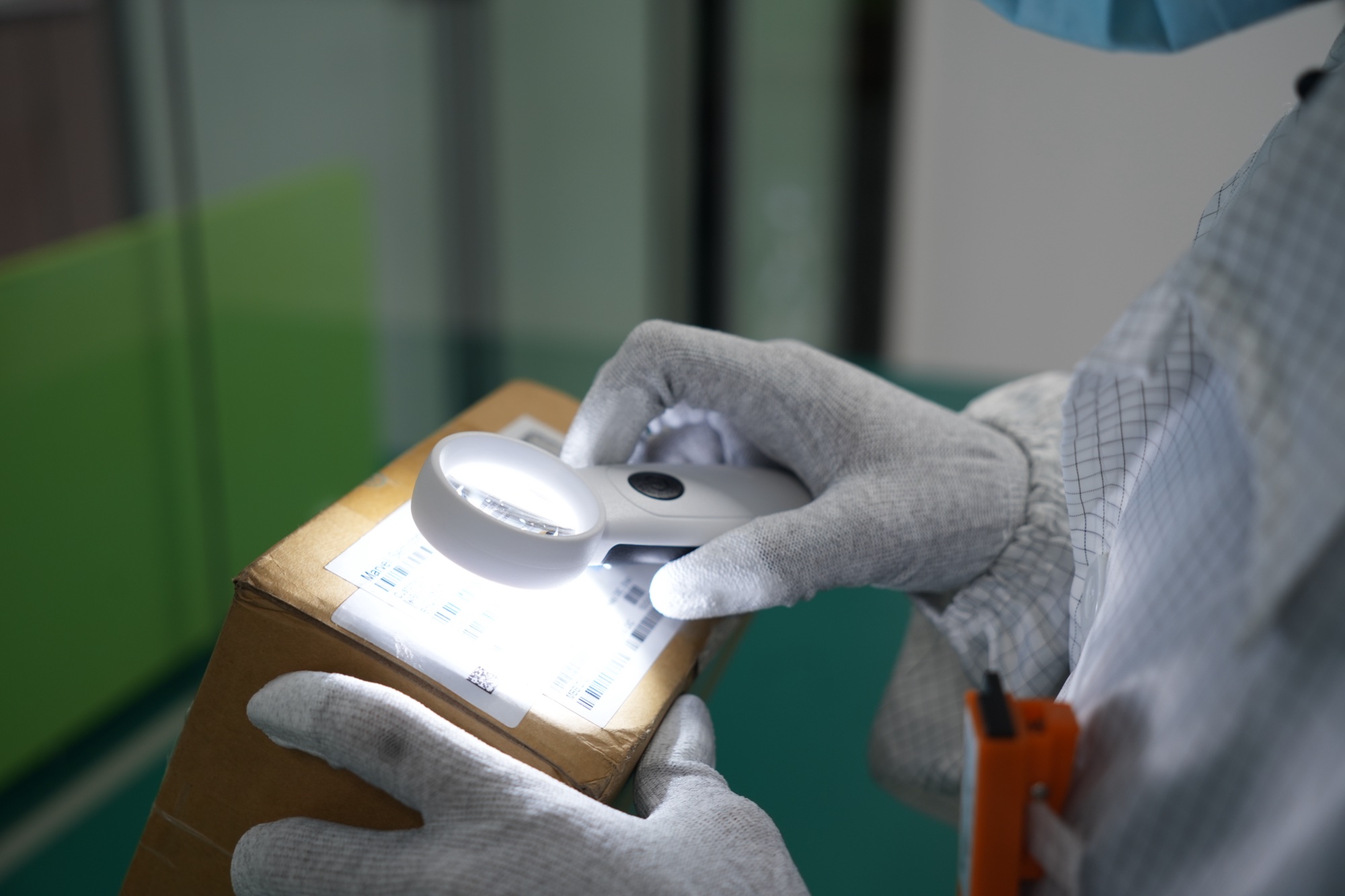Quality inspector examining a component package label under magnification